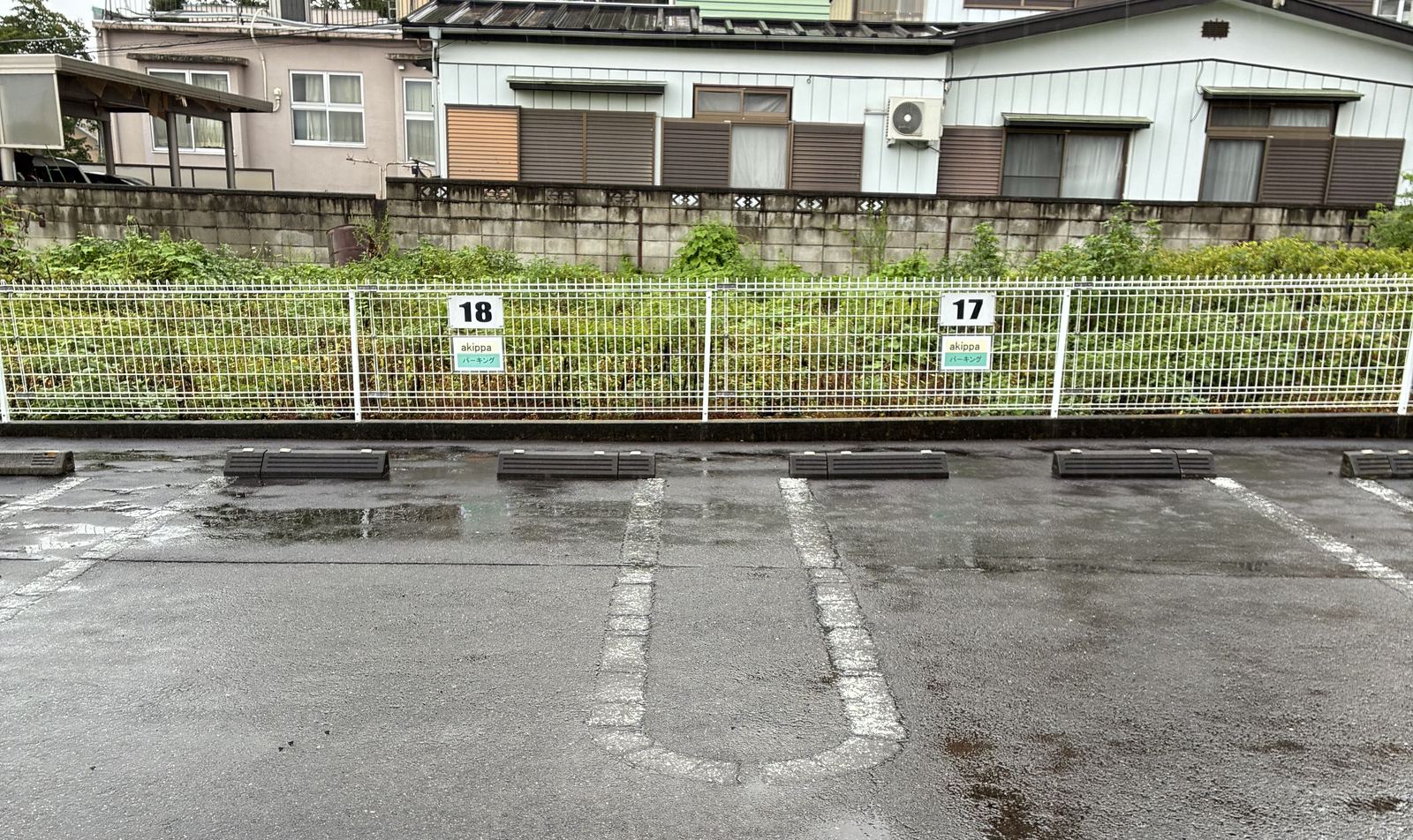 フェンスに取り付けられた17番・18番の区画番号プレートと、白線で区切られた駐車区画。